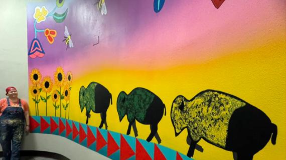 Mural of sunflowers, a sunrise sky, and bison.